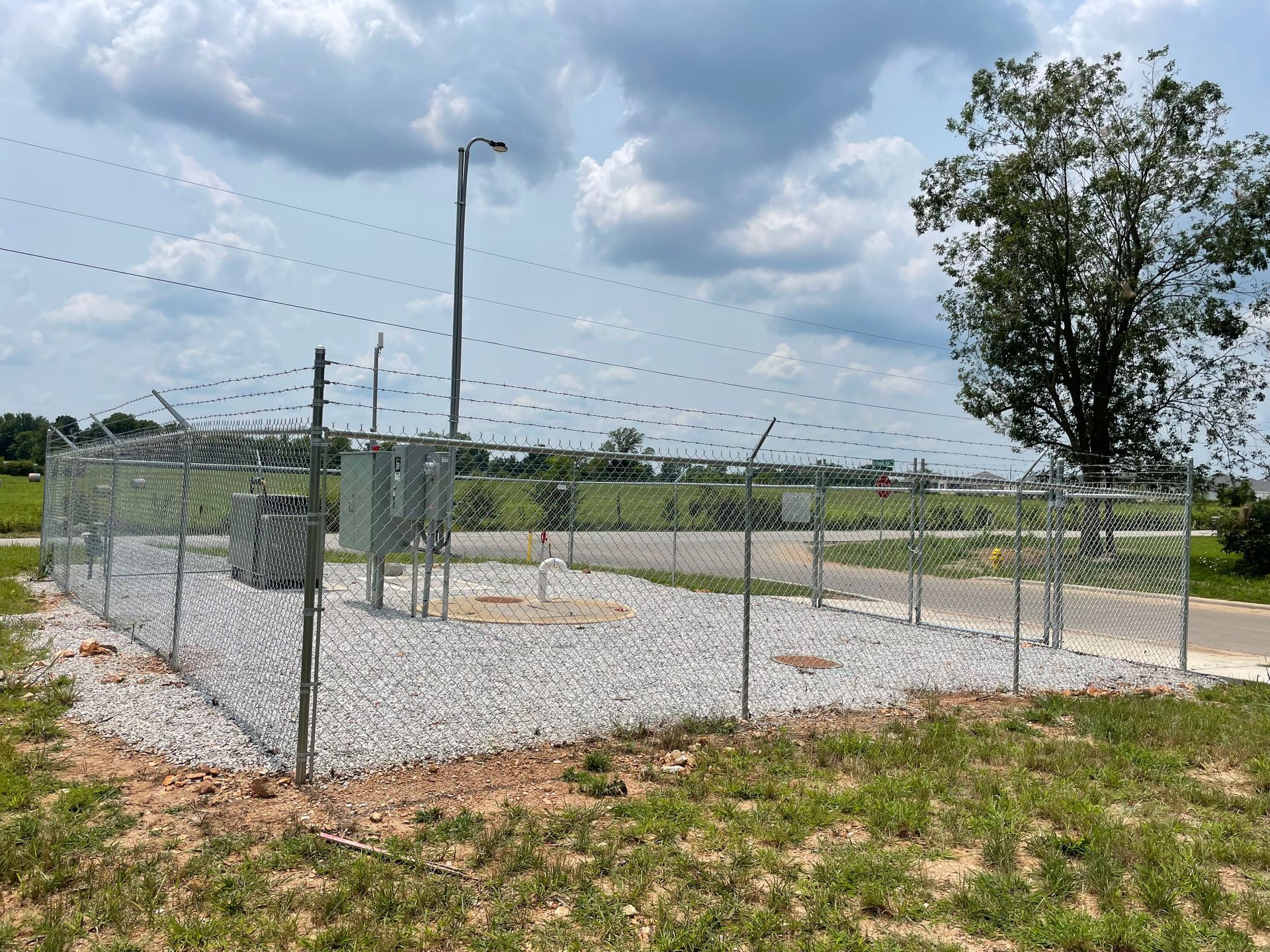 Data center building with metallic siding behind a tall fence, on a cloudy day.