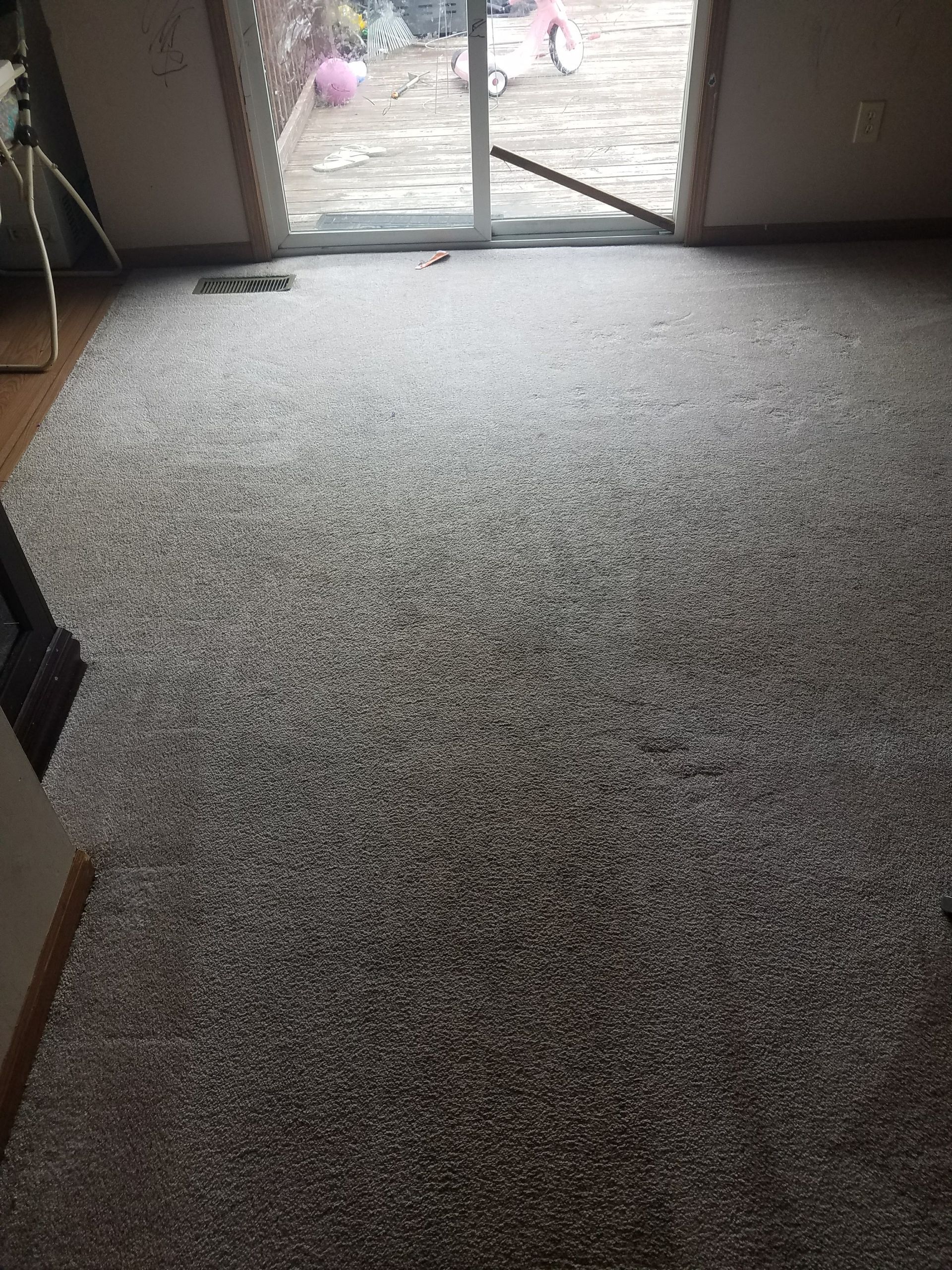A carpeted floor in a living room with a sliding glass door.