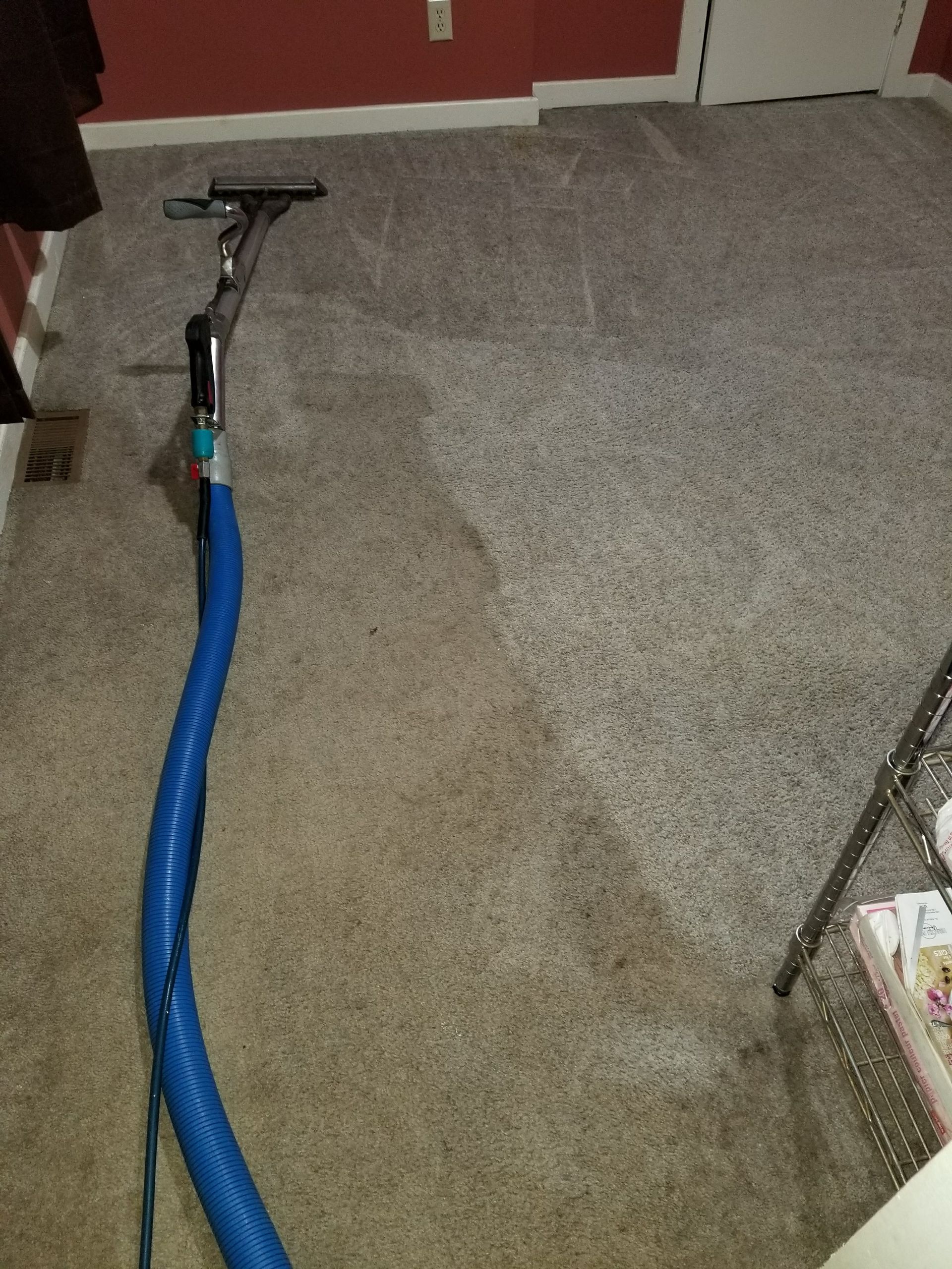 A vacuum cleaner is being used to clean a carpet in a room.