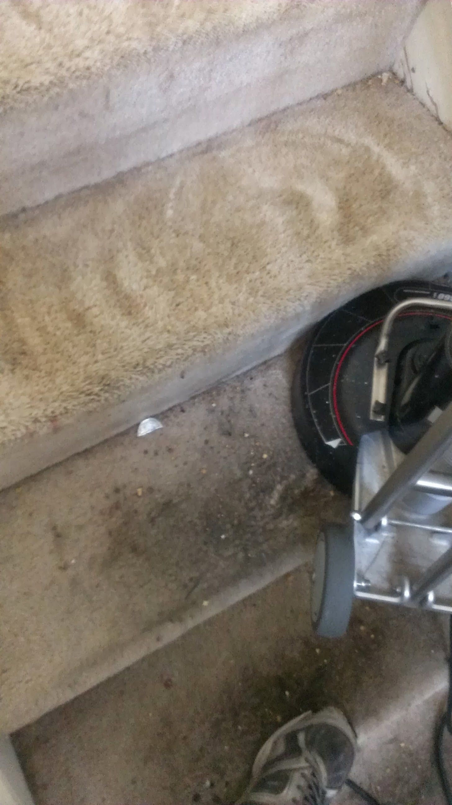 A vacuum cleaner is sitting on the floor next to a set of stairs.