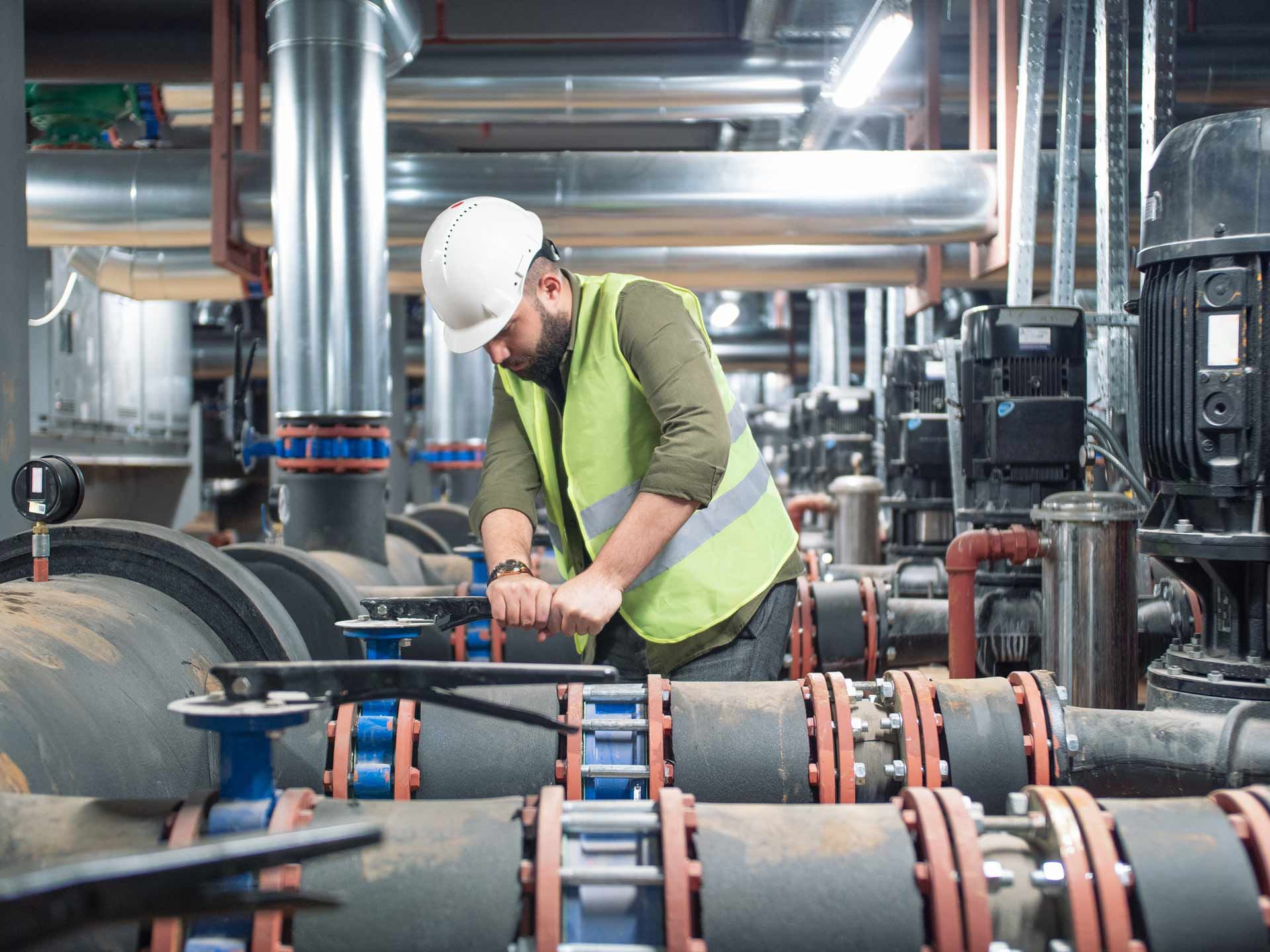 A man is working on pipes in a factory.