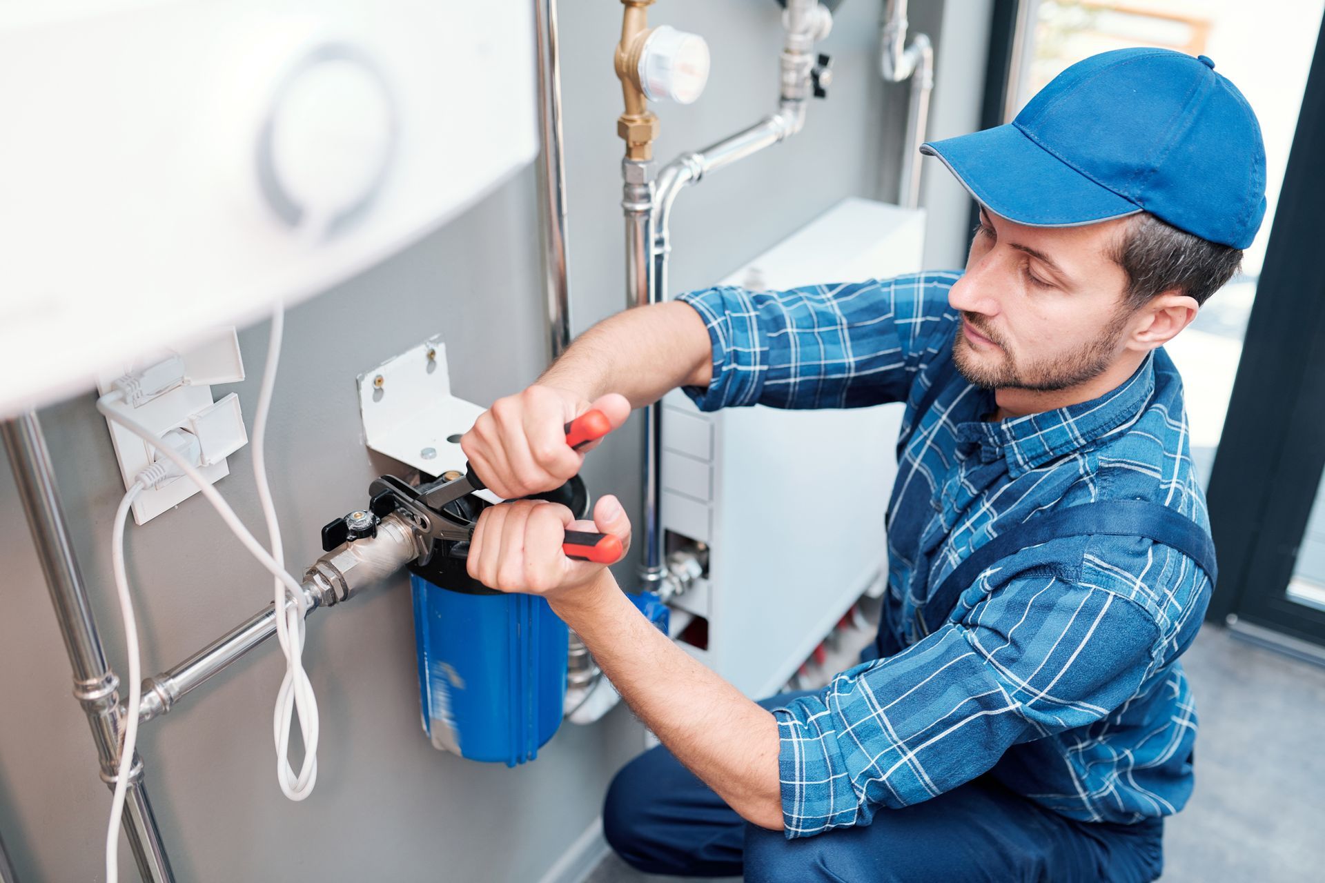 A plumber is working on a water filter in a bathroom.