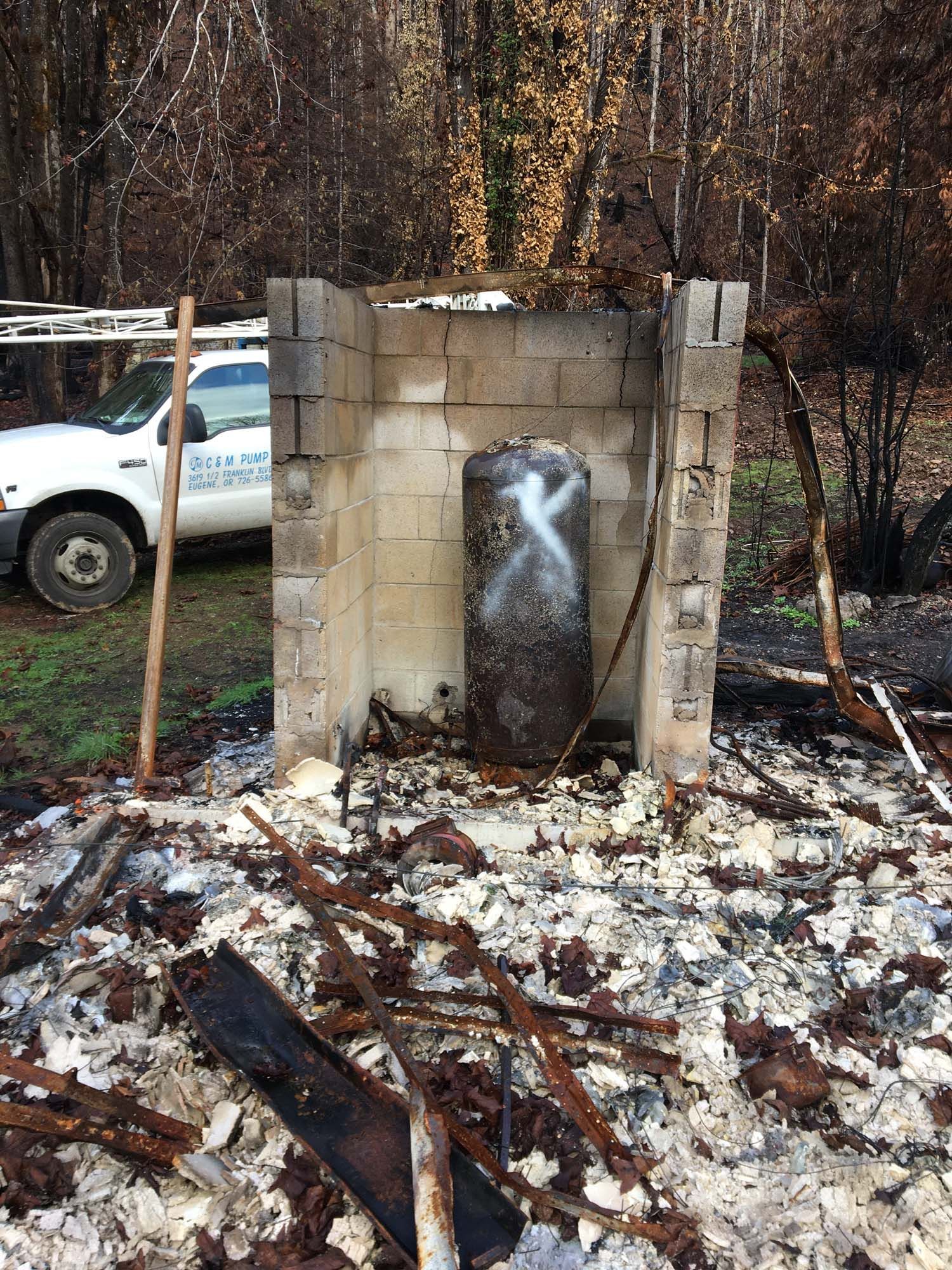 A solitary fire hydrant is positioned in the center of a charred building, symbolizing the impact of a recent fire.