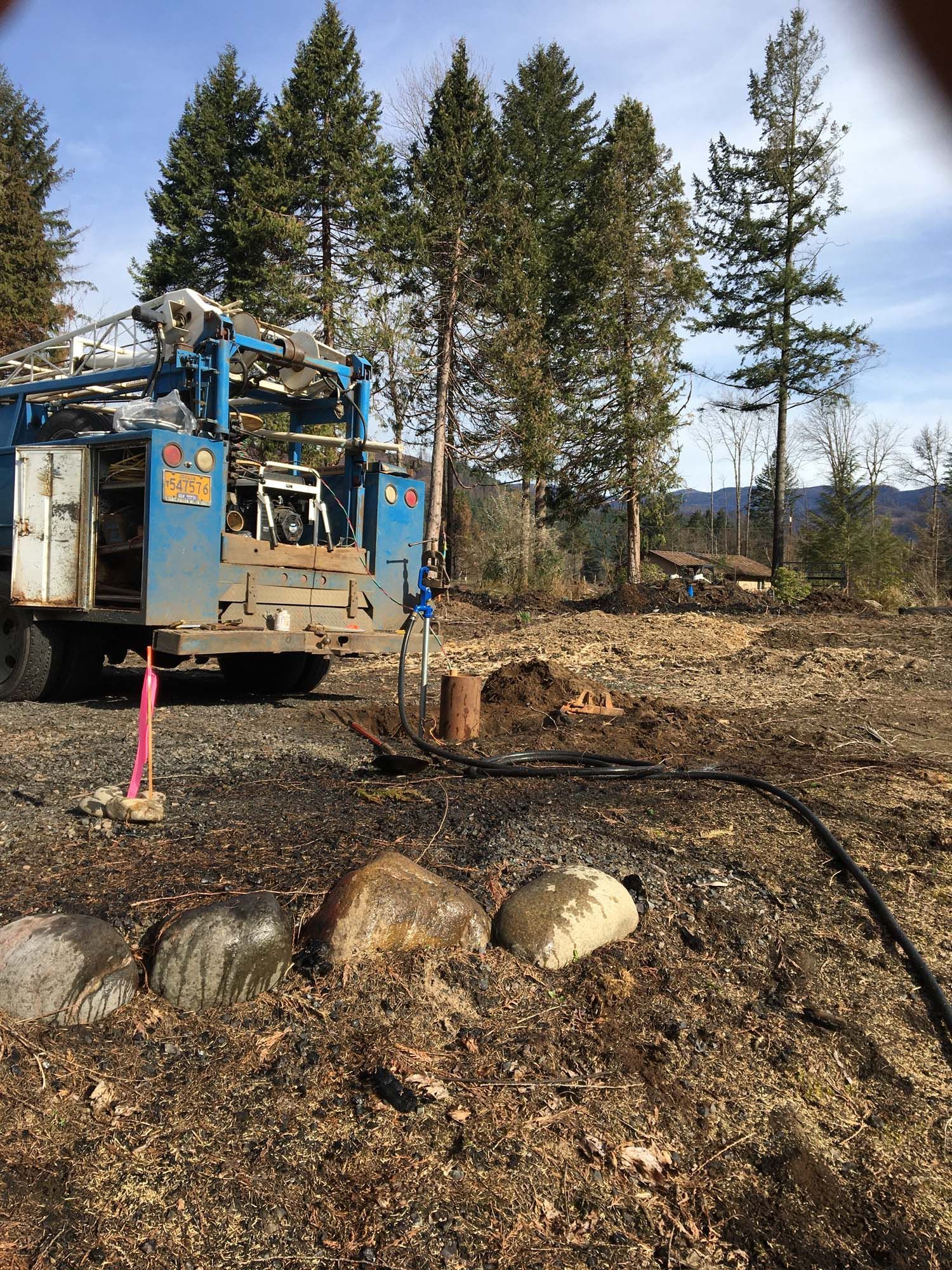 A blue truck is parked in the middle of a dirt field.