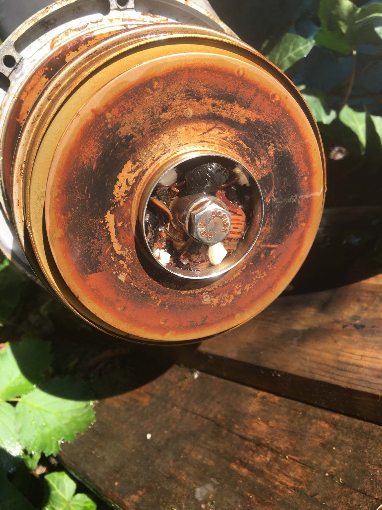 A close up of a rusty wheel on a wooden table.
