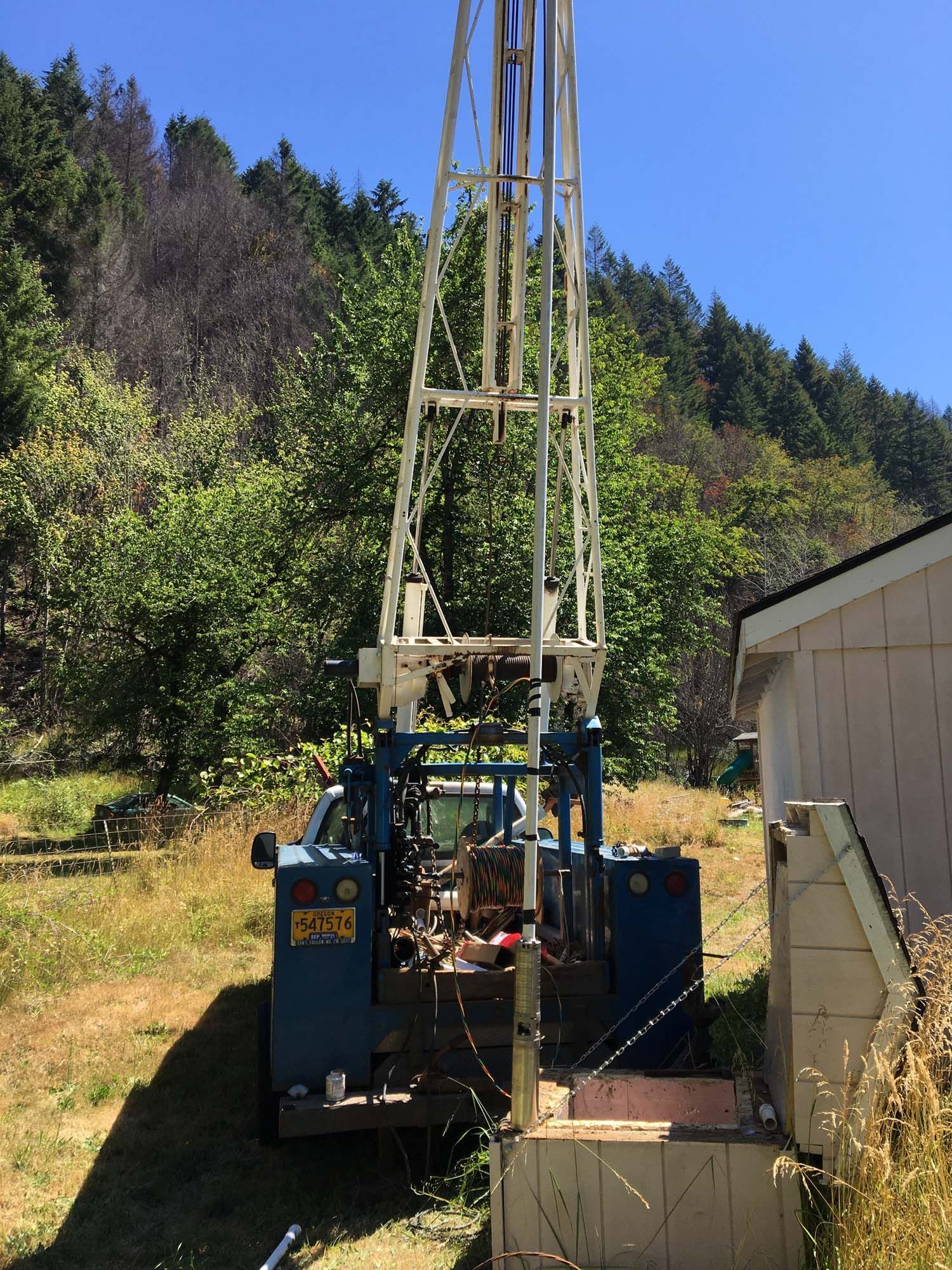 A blue truck is parked in a grassy field next to a house.