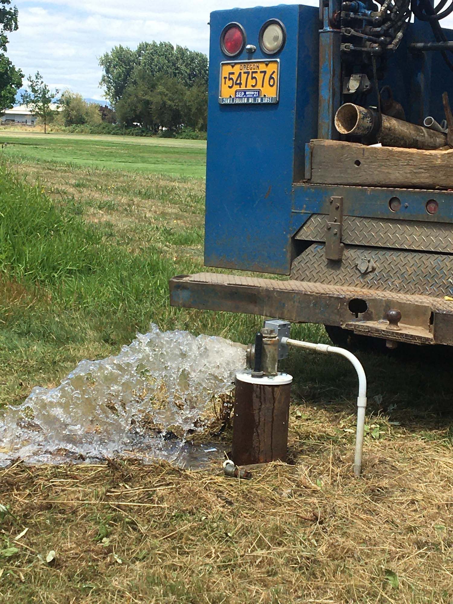A truck is pumping water from a well in a field.