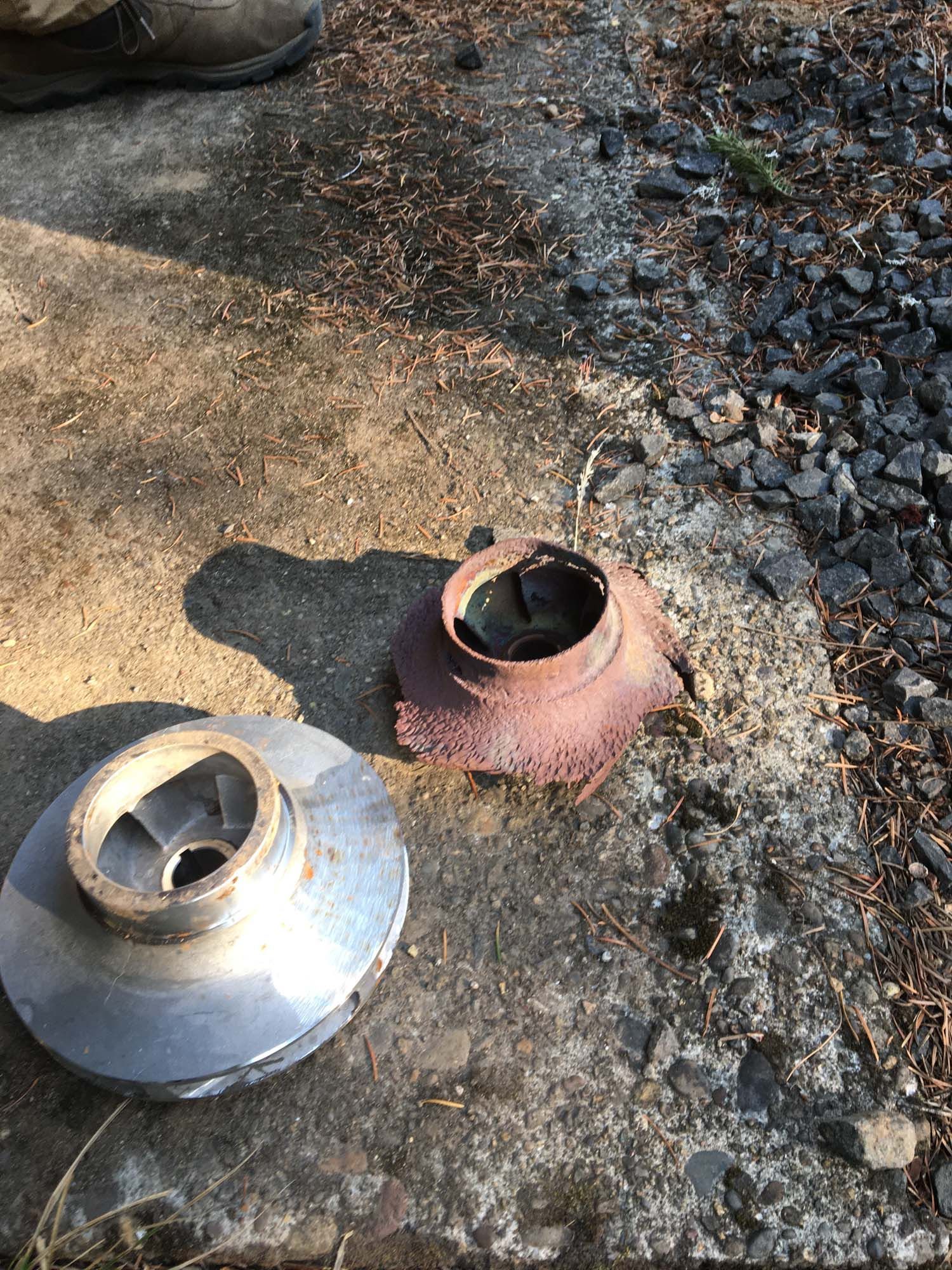 Two metal pieces are sitting on the ground next to each other.