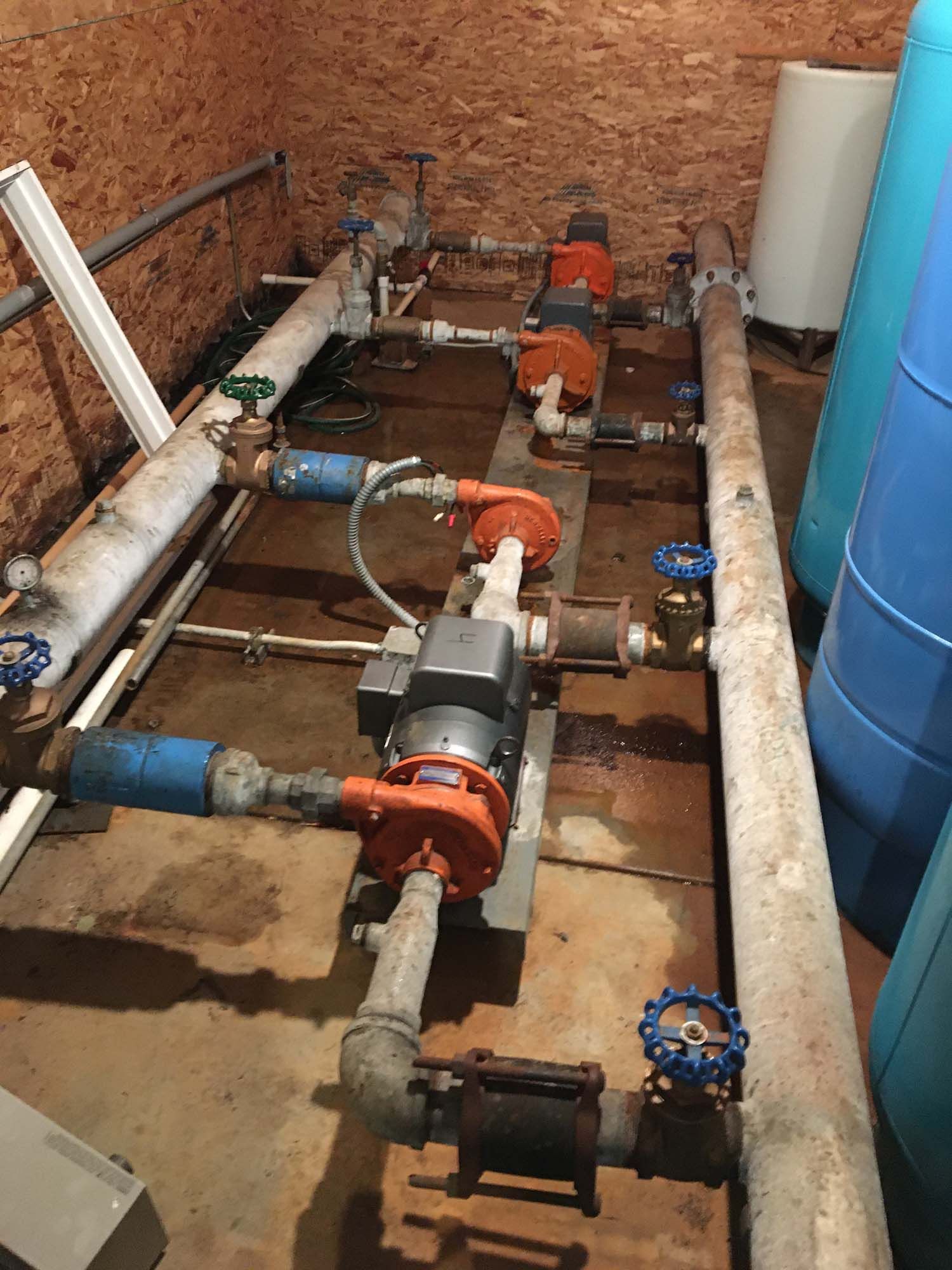 A room with a lot of pipes and valves on the floor.