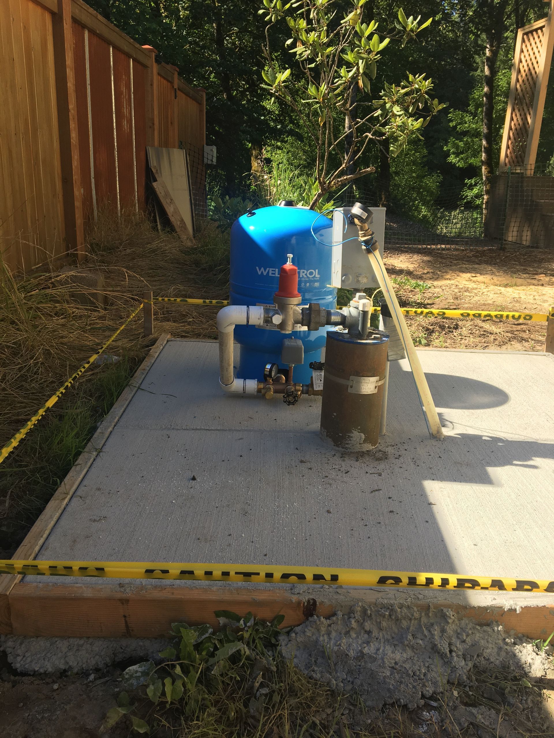 A water pump is sitting on a concrete platform with a caution tape around it.