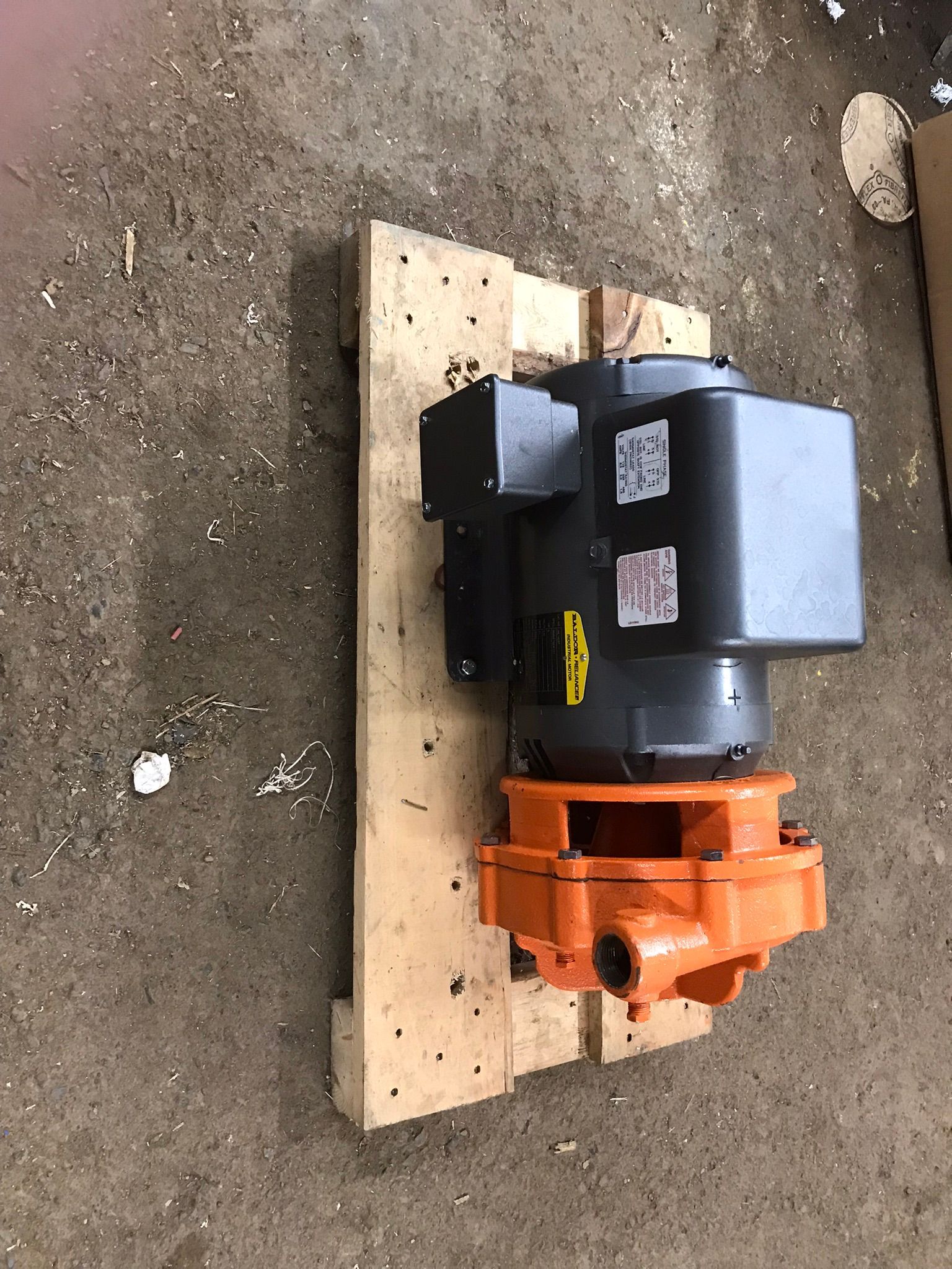 A motor is sitting on top of a wooden pallet.