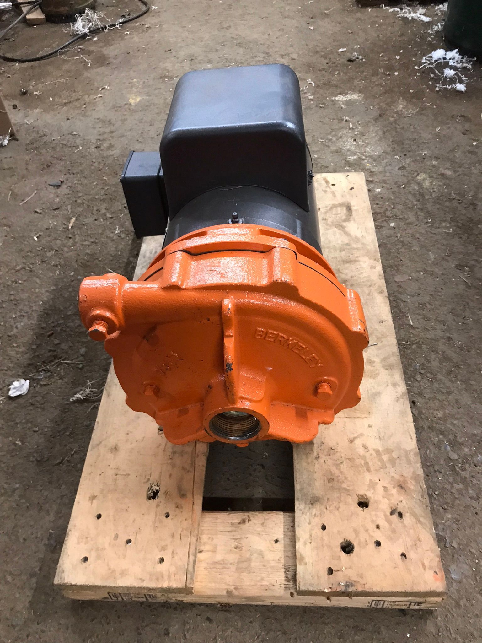 A large orange engine is sitting on top of a wooden pallet.