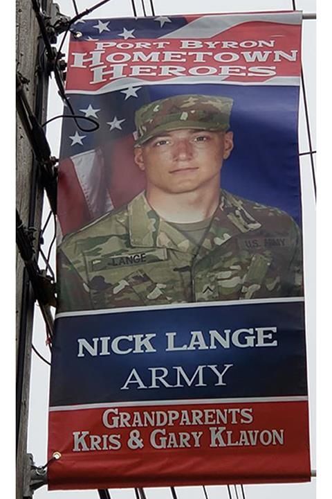 Banner honoring Nick Lange, an Army soldier, displayed in Port Byron, New York. It features a portrait of Lange in uniform, the American flag, and lists his grandparents.