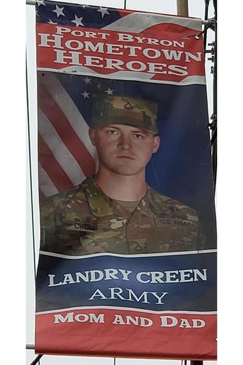 A banner honoring Landry Green, a soldier from Port Byron, Illinois. It has a photo of the soldier in uniform in front of an American flag.