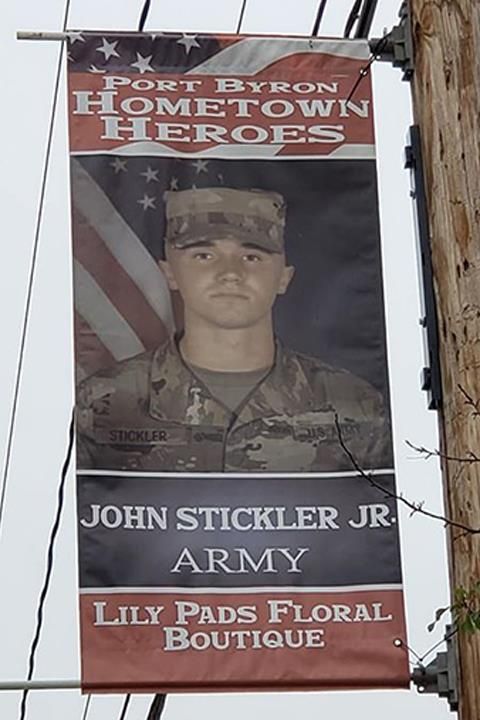Banner honoring John Stickler Jr., an Army soldier, as a Port Byron Hometown Hero. Includes his photo, the American flag, and the Lily Pads Floral Boutique logo.