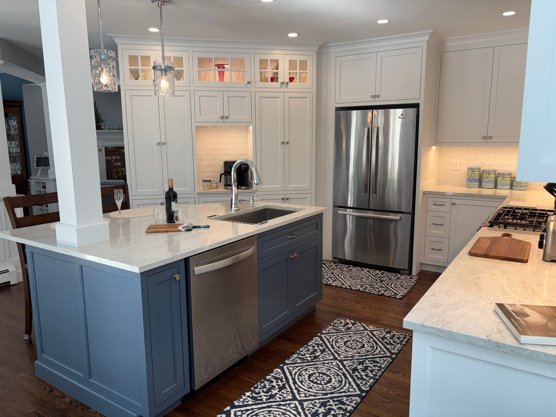 Kitchen with white cabinets, blue island, stainless steel appliances, and tile flooring.