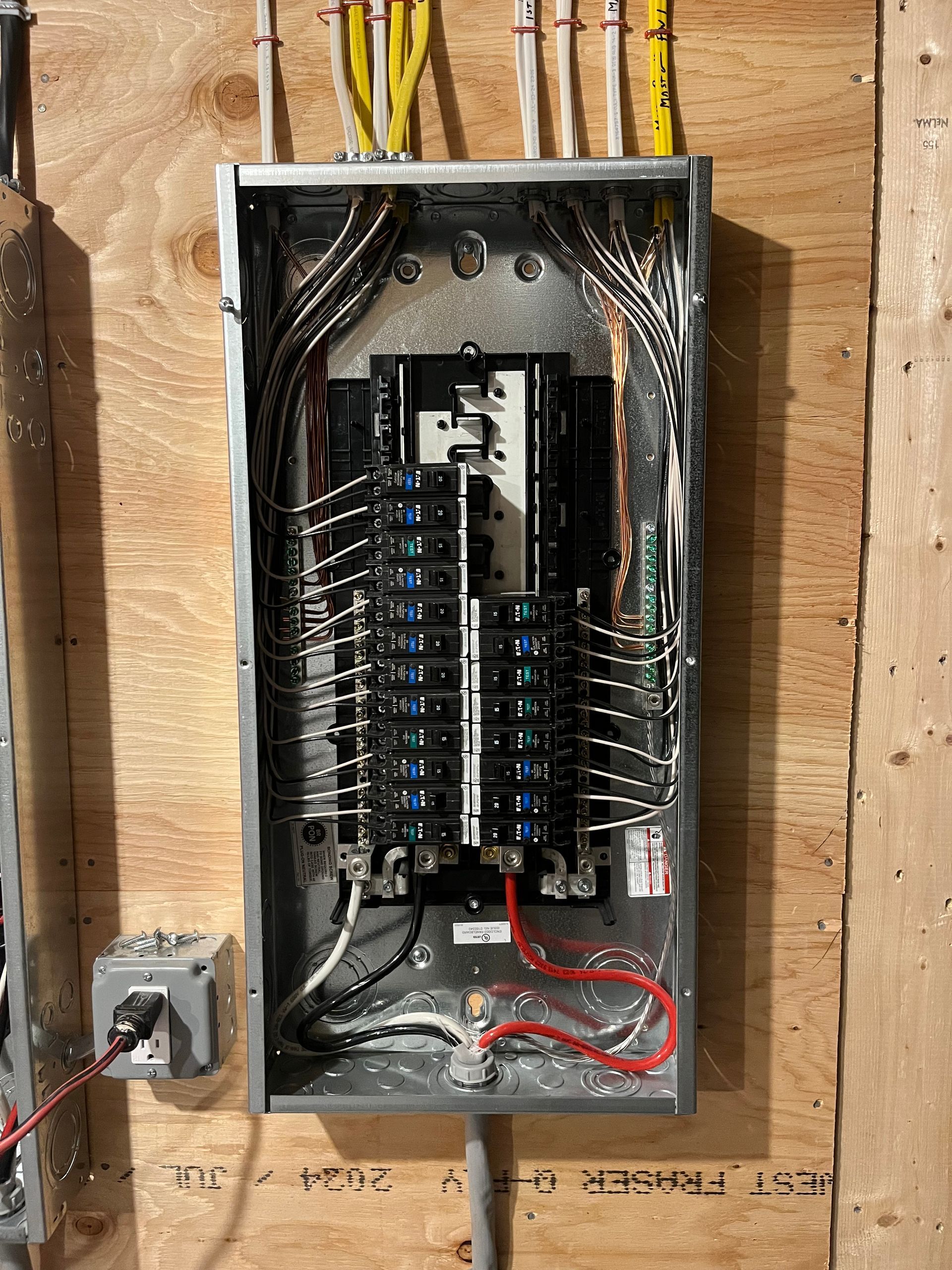 Electrical panel with many wires attached on a wooden wall.