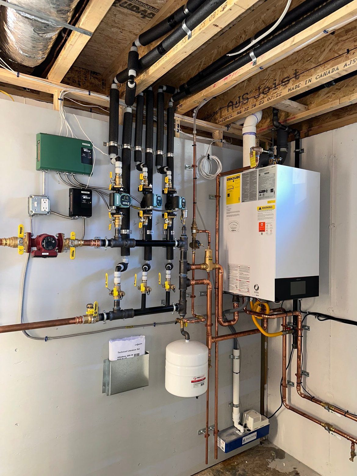 Heating system with pipes, valves, and a white boiler in a utility room.