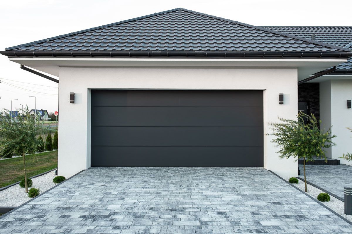 A white house with a black garage door and a black roof.