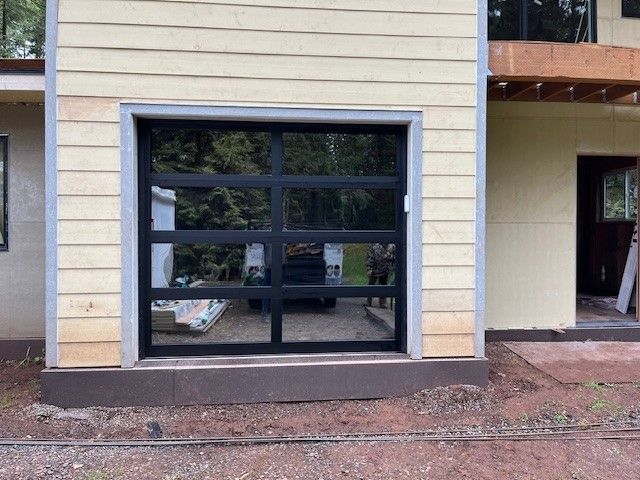 A house under construction with a black garage door