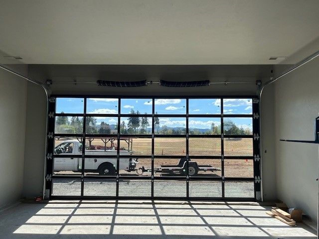 A large glass garage door with a truck parked in the background.
