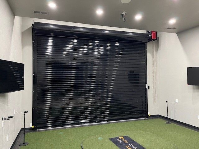 A room with a green carpet and a black shutter on the door.