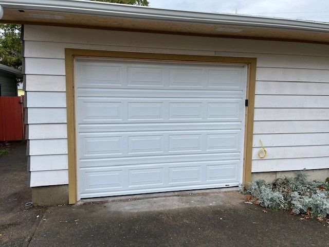 A white garage door is sitting on the side of a house.