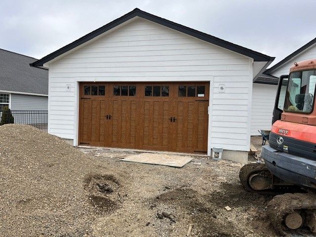 A large white garage with a wooden door is being built.