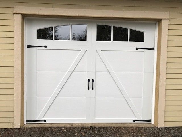 A white garage door with black handles and a window