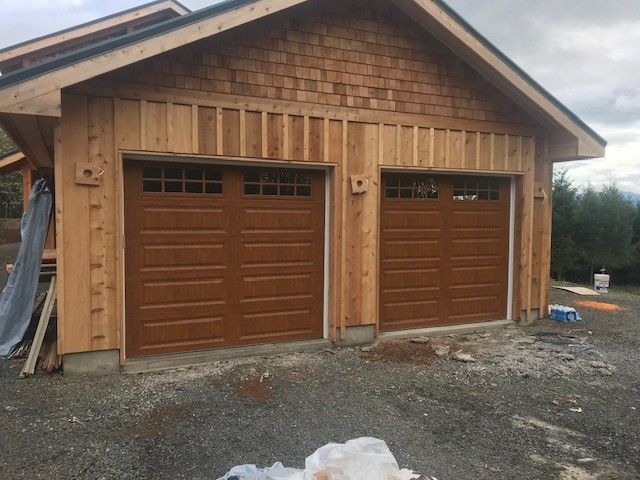 A garage with wooden siding and brown garage doors