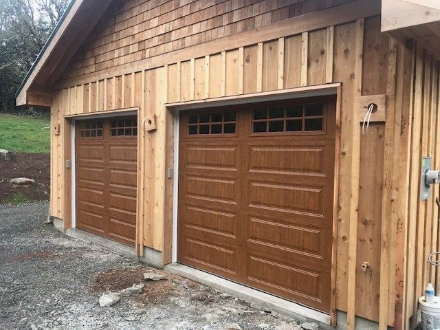 A garage with three brown garage doors and a wooden siding