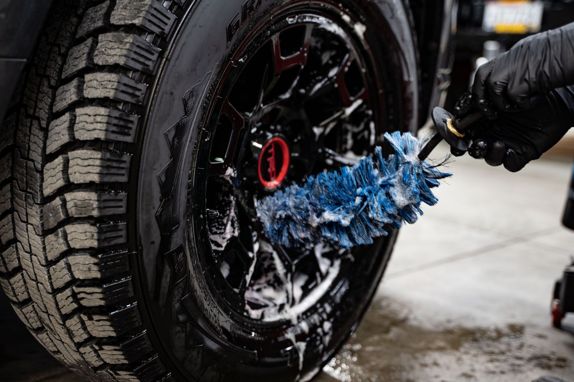 A person is cleaning a car wheel with a brush.