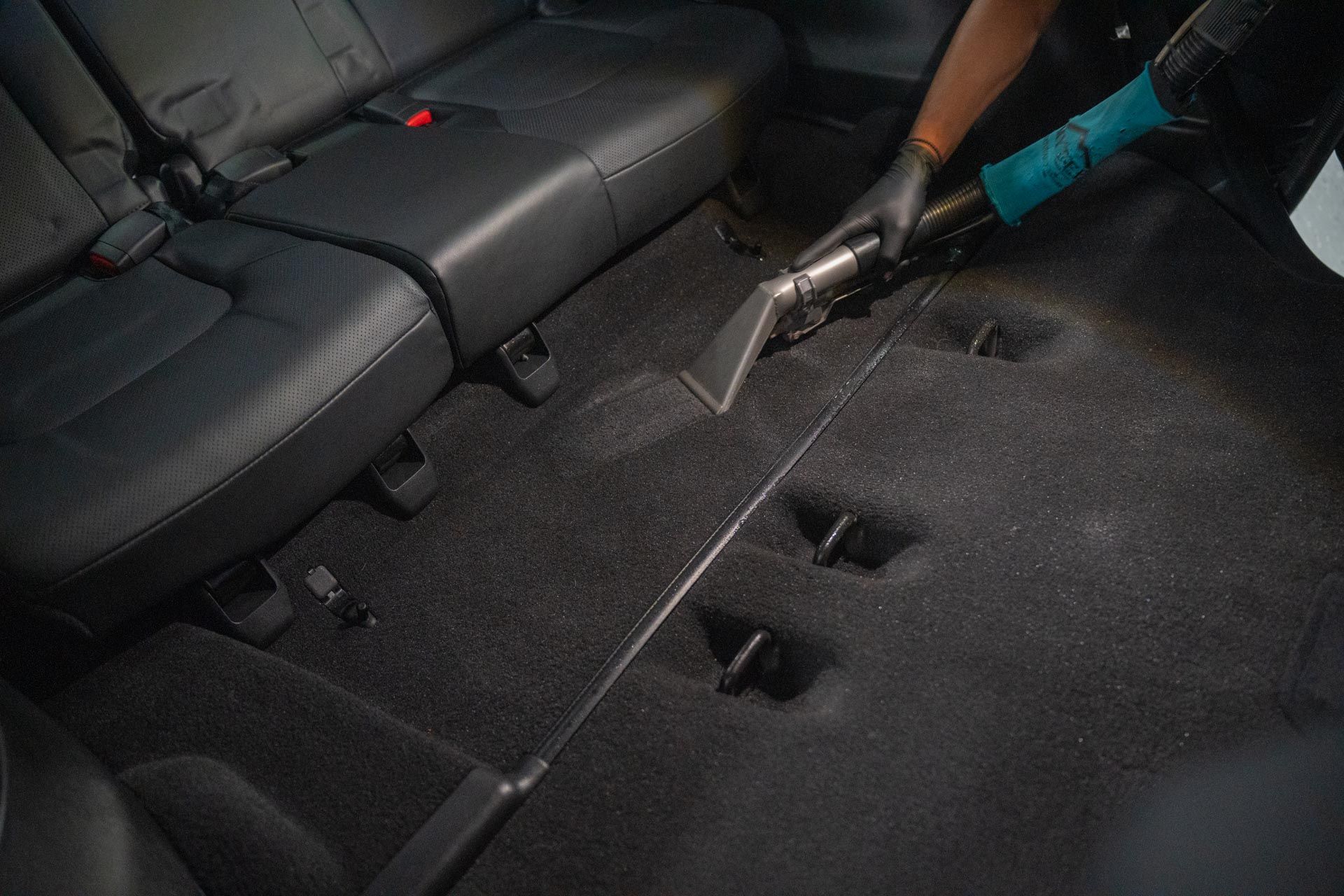 A person is using a vacuum cleaner to clean the floor of a car.