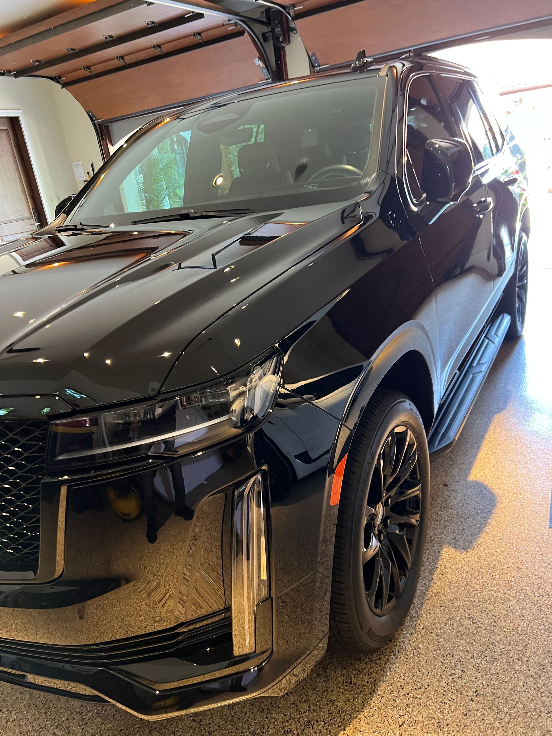 Black Cadillac Escalade parked in a garage; front view with gullwing doors open.
