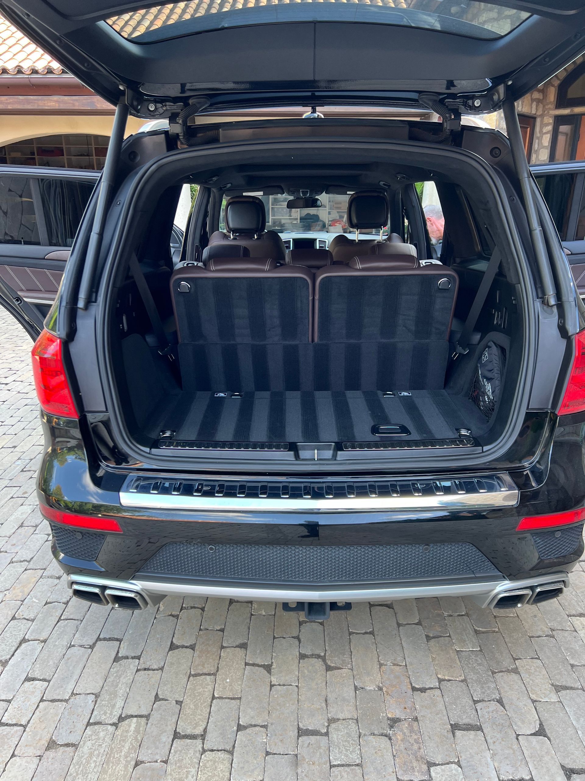 Black Mercedes SUV with open trunk, interior visible, parked on paved surface.