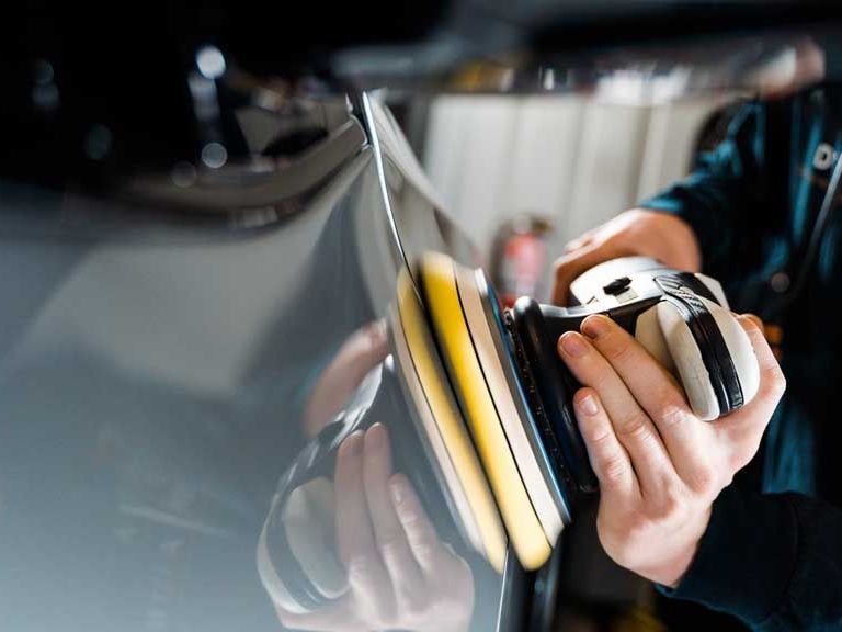 A person is polishing a car with a machine.