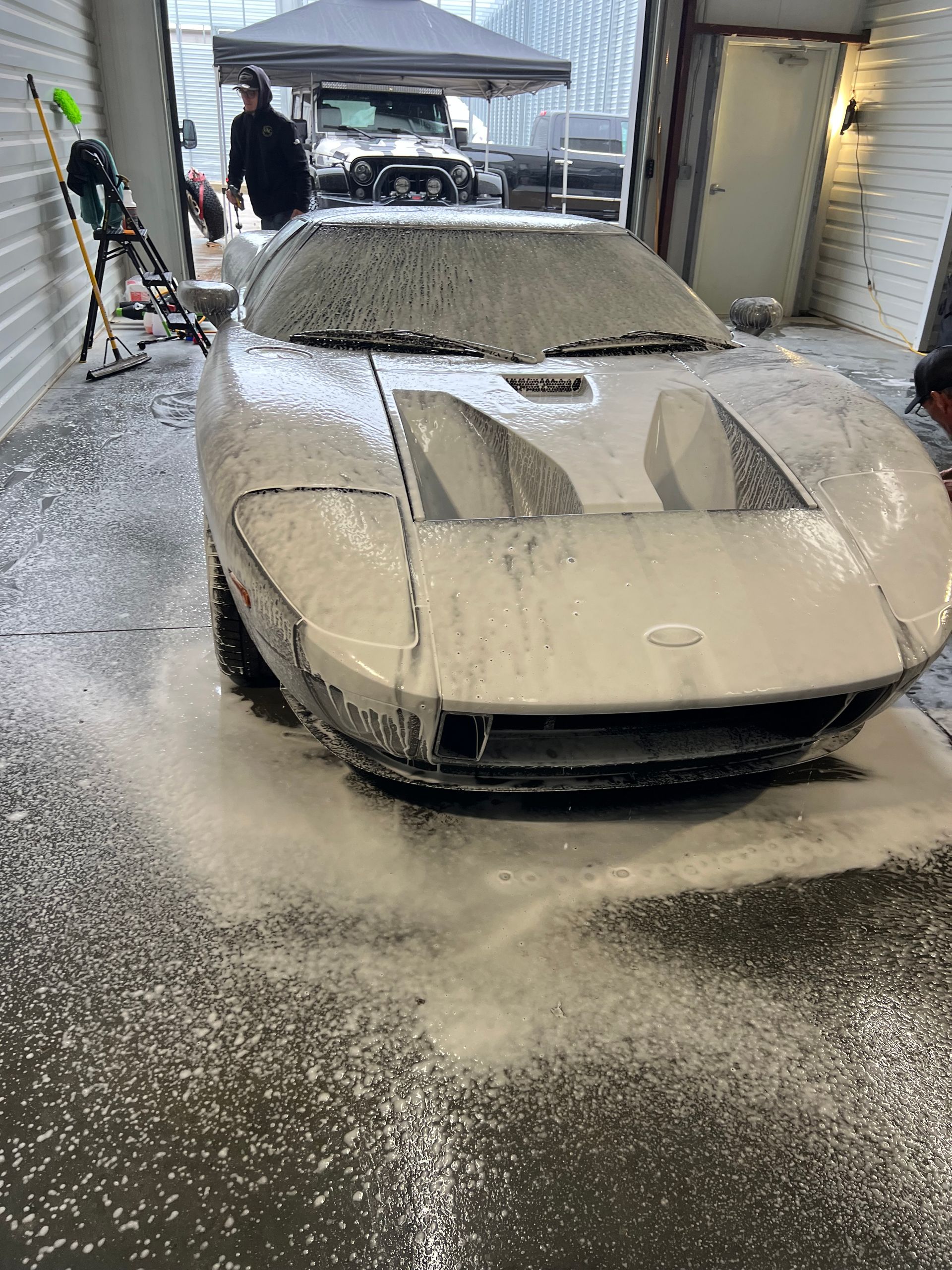 White Ford GT covered in car wash foam inside a garage.
