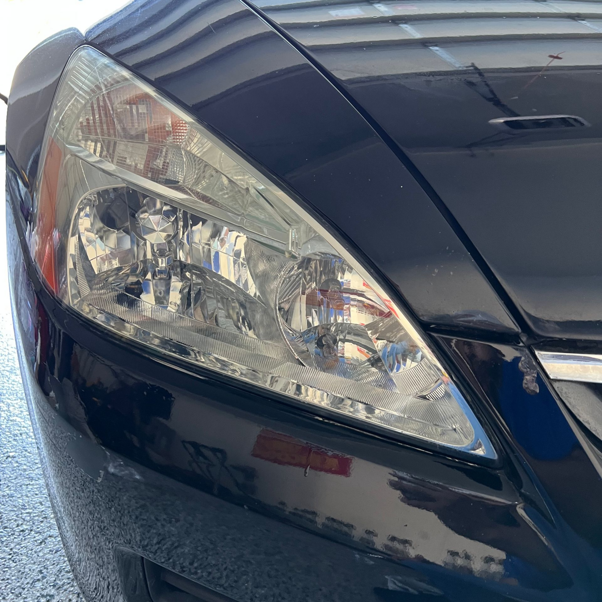 Black car's headlight close-up; bright, reflective, angled.