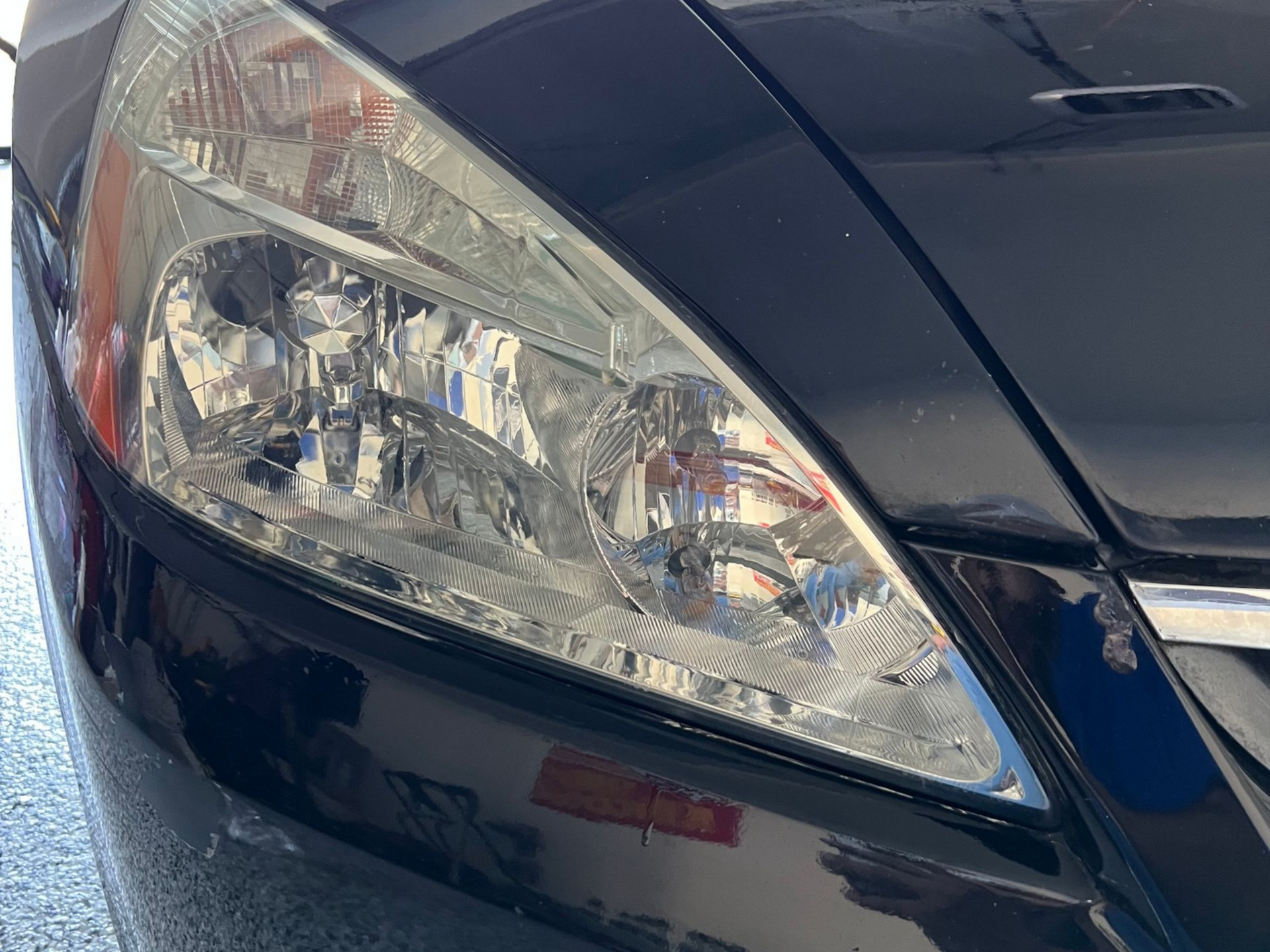 Black car's headlight close-up; bright, reflective, angled.