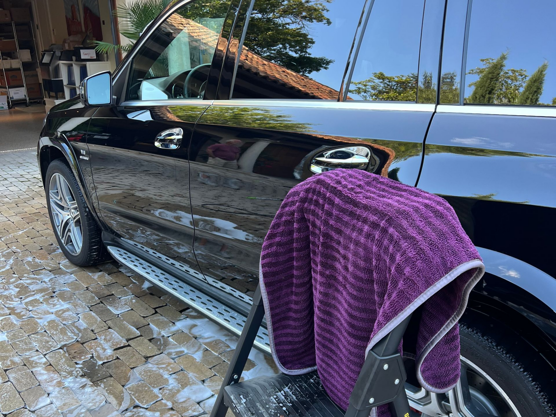 Black SUV being washed; purple microfiber towel on a step stool.