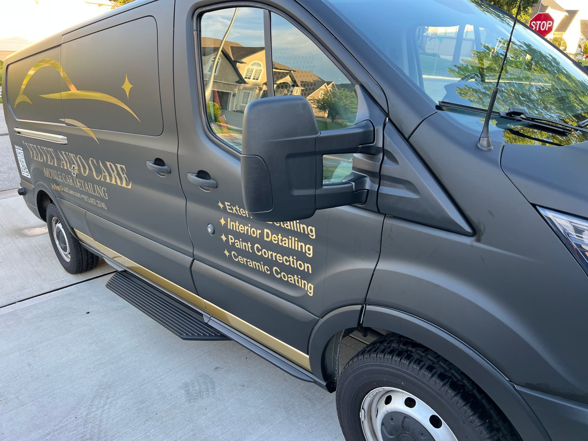 Dark gray van with gold trim and company logo, parked on a driveway.