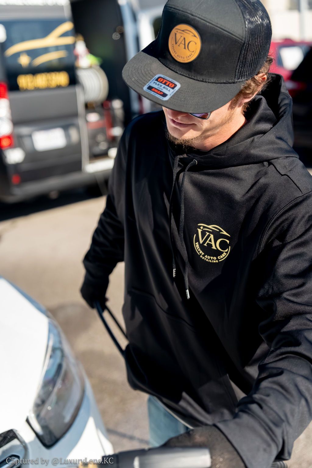 Person wearing black hoodie and hat, pulling something, logo 