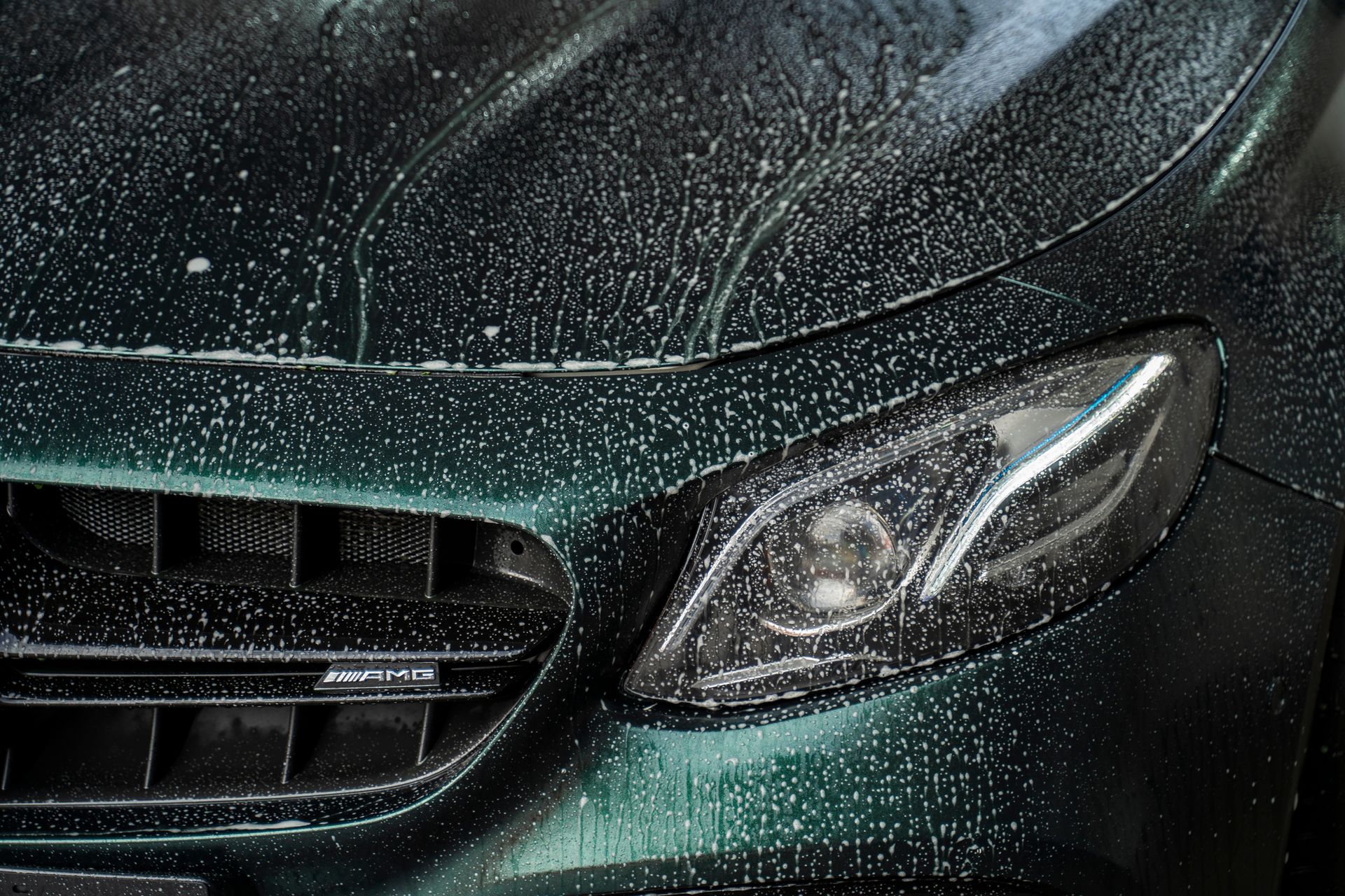 A person is polishing the hood of a blue car.