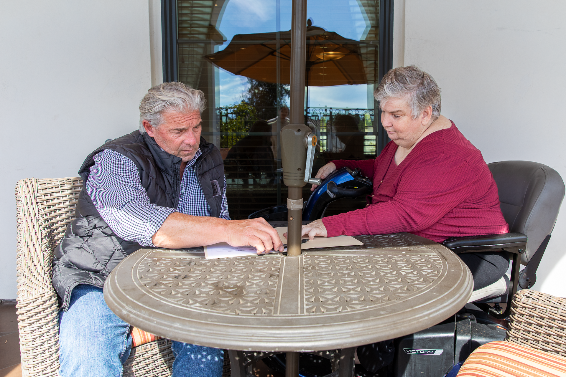 A man and a woman sit at a table under an umbrella