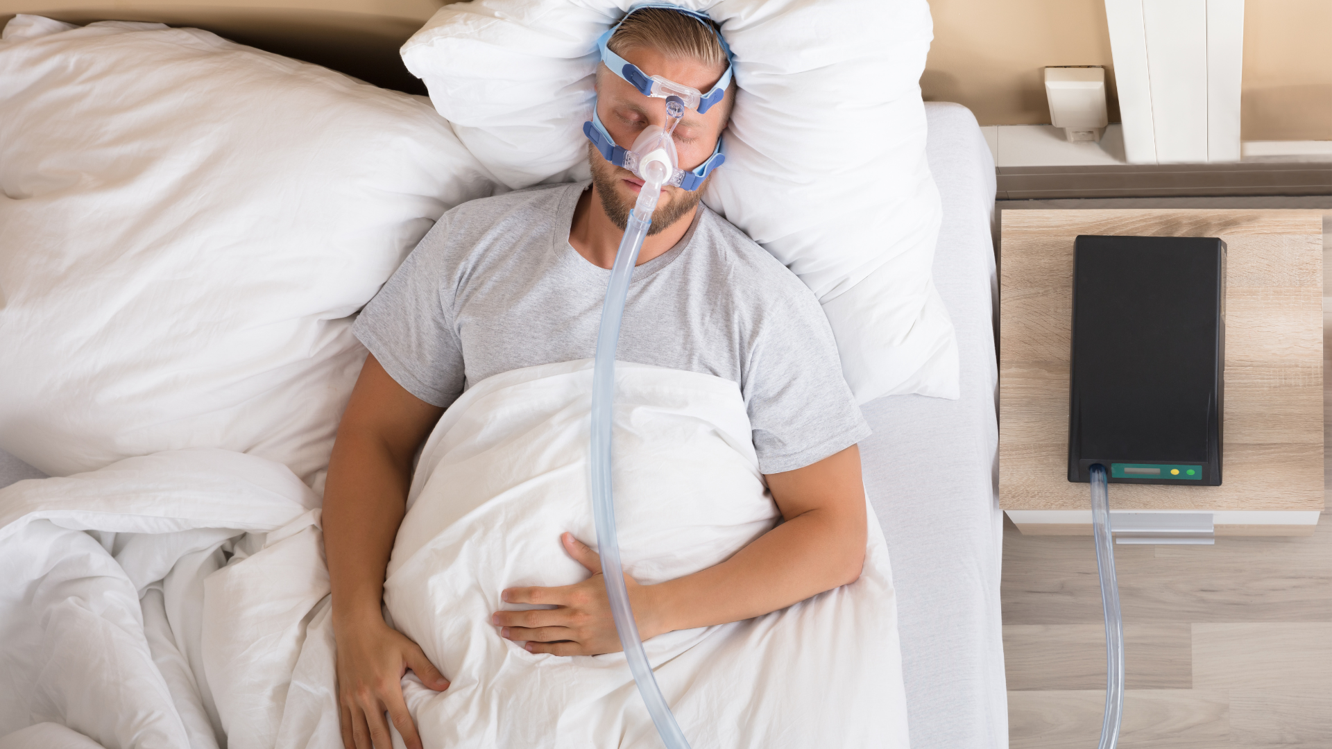 A man is laying in bed with an oxygen mask on his face.