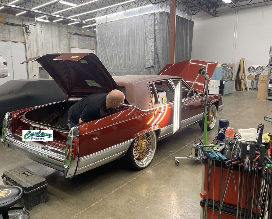 A man is working on a red car in a garage.