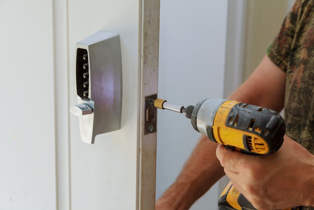 A Man is Using a Drill to Fix a Door Lock — Asset Locksmiths in Dalby, QLD
