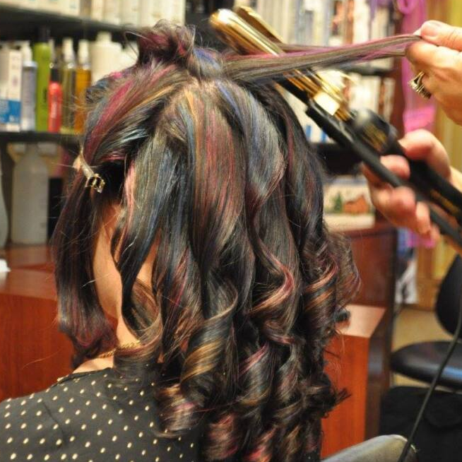 A woman is getting her hair straightened in a salon