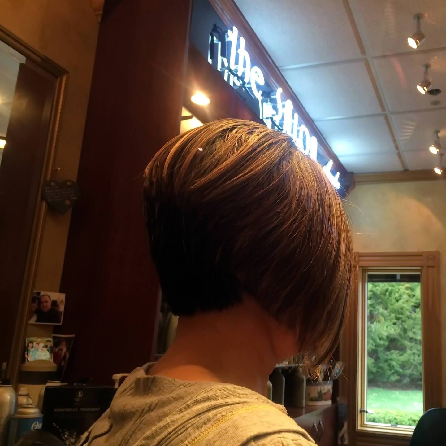 A woman 's back is shown in front of a sign that says the salon