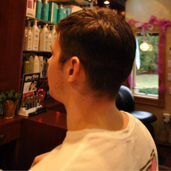 A man in a white shirt is sitting in front of a sign that says gray hair